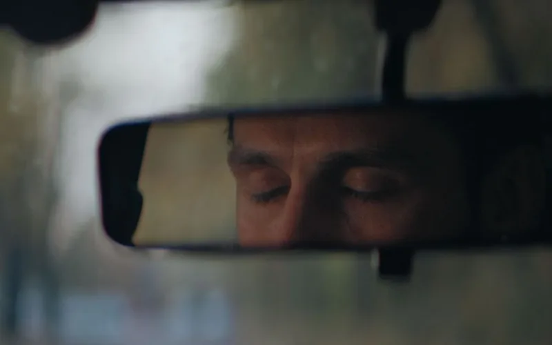Motorista com os olhos fechados refletido no retrovisor